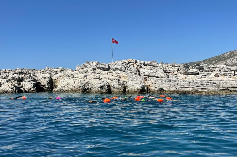 Gruppe mit orangen Schwimmbojen im Meer vor einer Felsinsel bei Bodrum